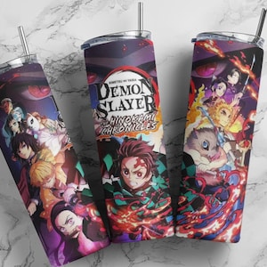 May include: Three stainless steel tumblers with lids and straws. Each tumbler features a vibrant anime-style graphic with characters and the text "Demon Slayer: The Hinokami Chronicles" against a purple and red background.