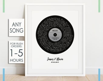 Può includere: Una stampa in bianco e nero di un disco in vinile con il testo della canzone "I Wanna Grow Old With You" dei Westlife. La stampa è incorniciata in una cornice bianca e include i nomi "James & Maria" e la data "07.03.2014".