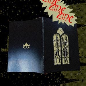 Puede incluir: Zine negro con detalles dorados, con un diseño de ventana estilizado y un pequeño emblema. La palabra "zine" se repite en rojo sobre una forma de estrella crema.