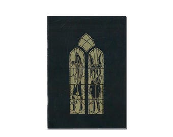 Puede incluir: Una cubierta de libro rectangular negra con un gráfico de color dorado de una ventana de vidrieras alta y arqueada. El diseño de la ventana está dividido en dos paneles verticales con líneas de plomo intrincadas y siluetas de figuras.