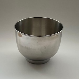 May include: A stainless steel mixing bowl with a rounded body and a wide, open top. The bowl has a small, circular base and a polished, reflective surface. The bowl is designed for food preparation and is suitable for various kitchen tasks.
