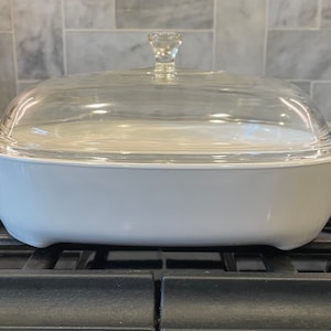 May include: White oval baking dish with a glass lid on a black stovetop.