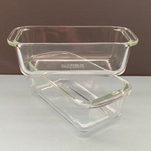 May include: Two clear glass rectangular baking dishes stacked on top of each other. The dishes have rounded corners and handles on each end. The glass is transparent, allowing a view through the dishes.
