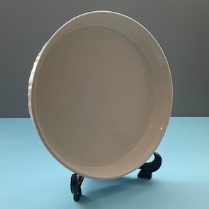 May include: White ceramic pie plate with a fluted edge, sitting on a black metal stand.