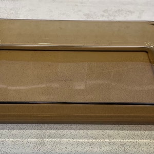 May include: A rectangular, amber-colored glass baking dish. The dish has a simple, classic design with slightly rounded corners and a smooth surface. It is empty and ready for use in the oven.