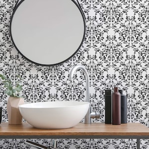 May include: A white bathroom sink with a chrome faucet and a round mirror above it. The wall behind the sink is covered in black and white damask wallpaper.