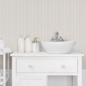 May include: White bathroom vanity with a white porcelain sink and chrome faucet. The vanity has a single drawer and a white countertop. The background is a white and gray chevron patterned wallpaper.