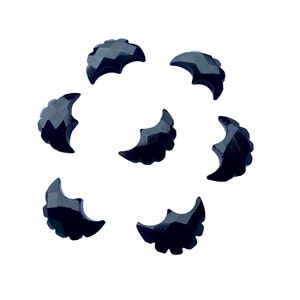 May include: Seven faceted black bat-shaped beads arranged in a circular pattern. Each bead has a detailed wing design and a textured surface, perfect for jewelry making or craft projects.