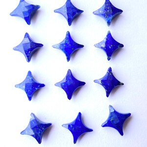 May include: Twelve blue star-shaped lapis lazuli gemstones. The gemstones are faceted and have a metallic sheen.
