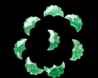 Puede incluir: Una colección de diez formas de media luna de piedra preciosa verde dispuestas en espiral sobre un fondo negro.