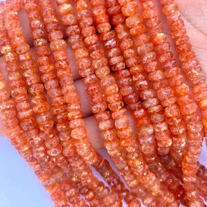 Puede incluir: Una hebra de cuentas de piedra de sol naranja, facetadas y pulidas, con una calidad brillante e iridiscente. Las cuentas están enhebradas en un hilo transparente y tienen aproximadamente 4 mm de diámetro.