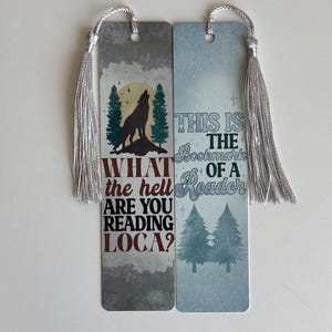 May include: Two bookmarks with a wolf and trees on a gray background. The text on the bookmarks reads "What the hell are you reading loca?" and "This is the bookmark of a reader".