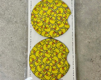 May include: Two yellow car coasters with a pattern of yellow rubber duckies. The coasters are packaged in a clear plastic bag with a white card that says "car coasters" and "handmade with love n care".