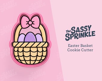 May include: Pink Easter basket cookie cutter with a bow on top and purple eggs inside. The cookie cutter is made of plastic and is designed to cut out cookies in the shape of an Easter basket.