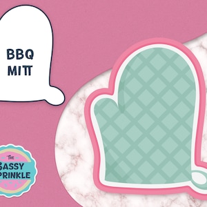 Può includere: Un tagliapasta a forma di guanto da forno di colore azzurro e rosa con un motivo a rombi. Il tagliapasta ha la forma di una mano con un pollice e quattro dita. Il testo "BBQ Mitt" è scritto sul contorno bianco del tagliapasta.