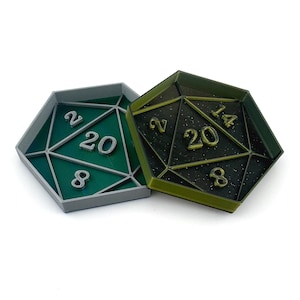 May include: Two 20-sided dice trays, one green and one black with gold glitter. The trays are shaped like a 20-sided die and have the numbers 2, 8, 14, and 20 printed on them.