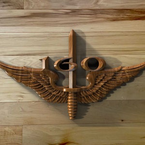 May include: A wooden carving of a military insignia with wings and a sword, featuring the number "160".