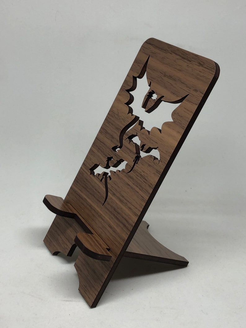 May include: A wooden phone stand with a dragon design cut out. The stand is brown and has a natural wood finish.