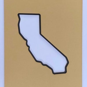 May include: A gold-colored background with a black outline of the state of California cut out of the center.