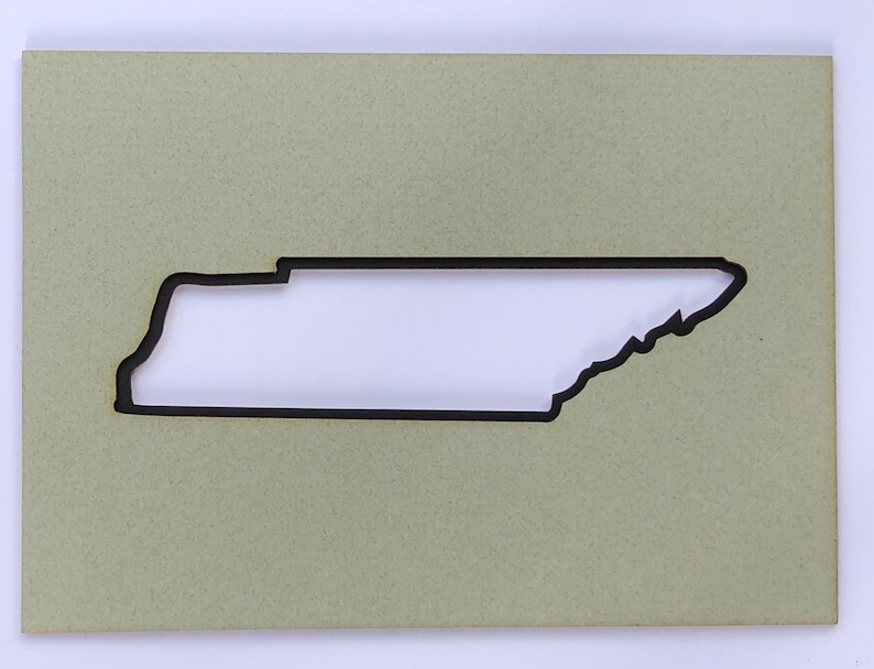 May include: A light green wooden plaque with a cutout of the state of Tennessee. The cutout is black and the plaque has a textured surface.