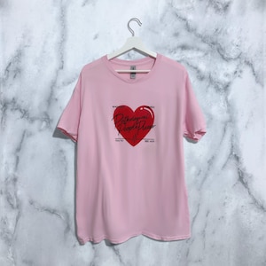 Könnte beinhalten: Pinkes T-Shirt mit einem roten Herz-Motiv, auf dem "Pathological People Pleaser" steht. Der Text "Who else" befindet sich über dem Herzen und "wanted" rechts neben dem Herzen. Der Text "You to" befindet sich unter dem Herzen links und "See her" unter dem Herzen rechts.