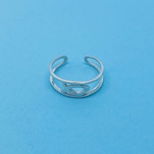 Puede incluir: Un anillo ajustable de plata con un símbolo de pez recortado.