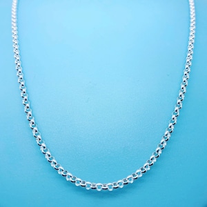 Op de afbeelding: Een zilveren kettingketting op een lichtblauwe achtergrond.