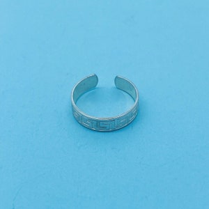 Puede incluir: Anillo de dedo del pie de plata con un diseño de llave griega.