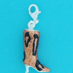 May include: A silver charm in the shape of a boot with a leopard print design. The boot has a high heel and is made of metal with a shiny finish.