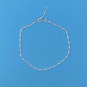 Peut inclure: Un bracelet en argent avec une chaîne fine et des maillons ronds. Le bracelet est doté d'un fermoir à mousqueton.