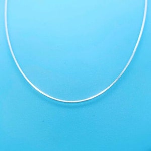 May include: A silver chain necklace on a blue background.