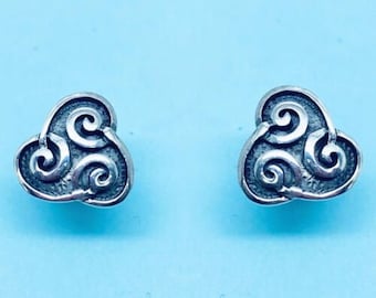 May include: A pair of silver earrings with a swirling, three-leaf design. The earrings are small and delicate.