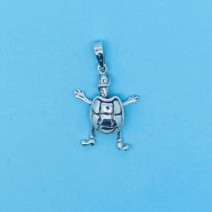 May include: A silver charm pendant in the shape of a turtle with outstretched arms and legs. The turtle has a detailed shell and a smooth, polished finish.