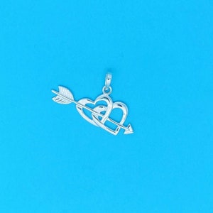 May include: Silver pendant featuring two intertwined hearts pierced by an arrow. The pendant is a romantic symbol of love and commitment.