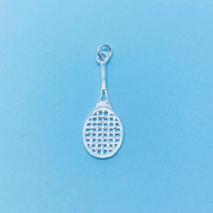 Pode incluir: Um amuleto de raquete de ténis de prata com um padrão de cordas detalhado.