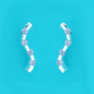 Puede incluir: Un par de pendientes de plata con un diseño curvo y pequeñas piedras transparentes.