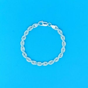 Könnte beinhalten: Ein silbernes Seilkettenarmband mit einem Karabinerverschluss.