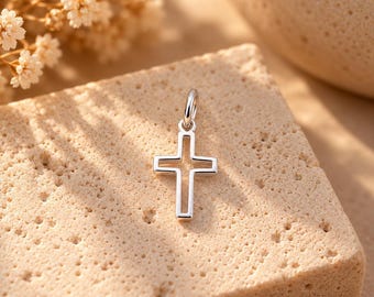 May include: A silver-toned metal cross pendant featuring an open, hollow center design. The cross has a smooth, polished finish and includes a small circular jump ring at the top for attachment to a chain or cord, presented as a single jewelry piece.