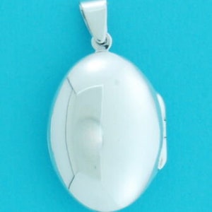 May include: A silver oval locket pendant with a smooth, shiny surface. The locket has a hinged opening on the side.