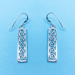 May include: A pair of silver dangle earrings with a rectangular design featuring an intricate Celtic knot pattern.