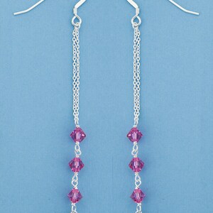 May include: A pair of silver dangle earrings with a chain design and pink and dark gray crystal beads.
