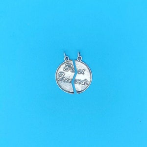 May include: Two silver charms that fit together to form a circle. The charms are engraved with the words "Best Friends".