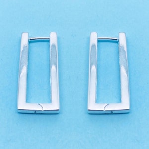 May include: A pair of silver hoop earrings with a rectangular shape.