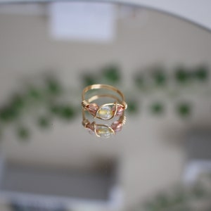 May include: A gold wire ring with a clear gemstone and pink beads.