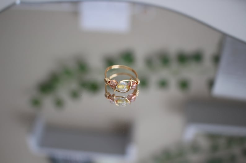 May include: A gold wire ring with a clear gemstone and pink beads.