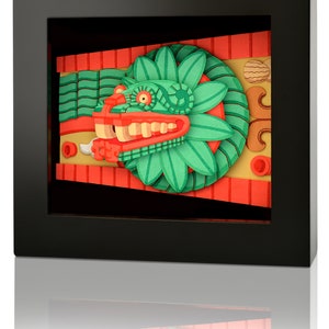 May include: A framed paper art piece depicting a green and red mythical creature with a toothy grin. The creature is set against a background of red and yellow stripes.