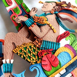 May include: A colorful paper mache sculpture of a figure with a blue and green patterned skirt, a red and green patterned top, and a blue and green patterned headdress. The figure is sitting on a colorful platform with a green, red, and blue design.