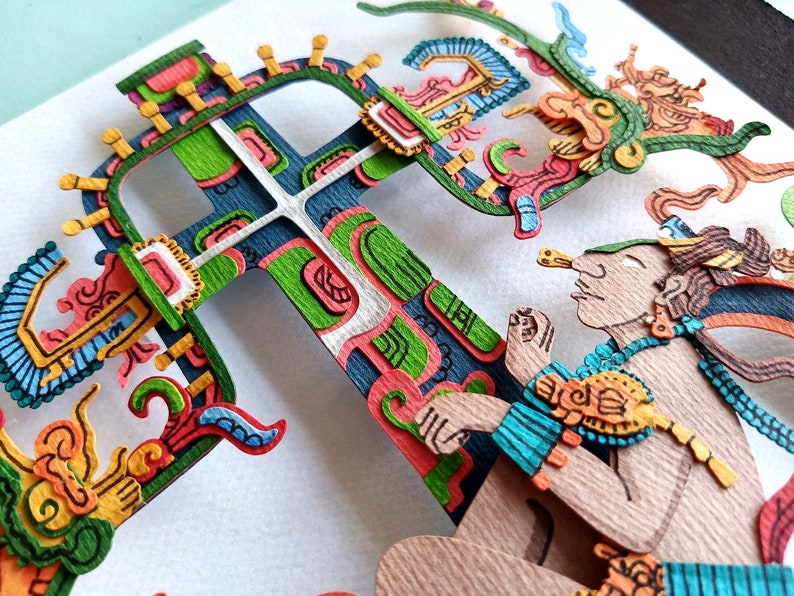 May include: A colorful paper cut-out art piece depicting a figure with a headdress and a large, intricate cross-shaped structure. The figure is holding a small object in its hand. The artwork is made of paper and is painted in various colors, including green, blue, yellow, and red.