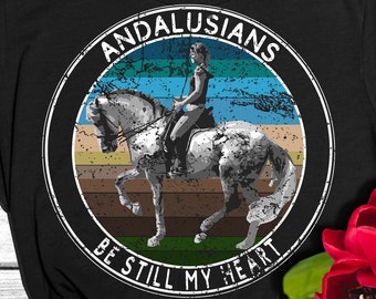 Puede incluir: Camiseta negra con un gráfico circular de estilo vintage que presenta un caballo andaluz blanco y un jinete. El texto "Andalusians Be Still My Heart" está impreso en blanco alrededor del círculo.