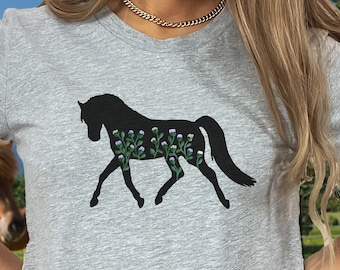 May include: A gray t-shirt with a black silhouette of a horse with purple flowers on its body. The horse is facing the right side of the image.